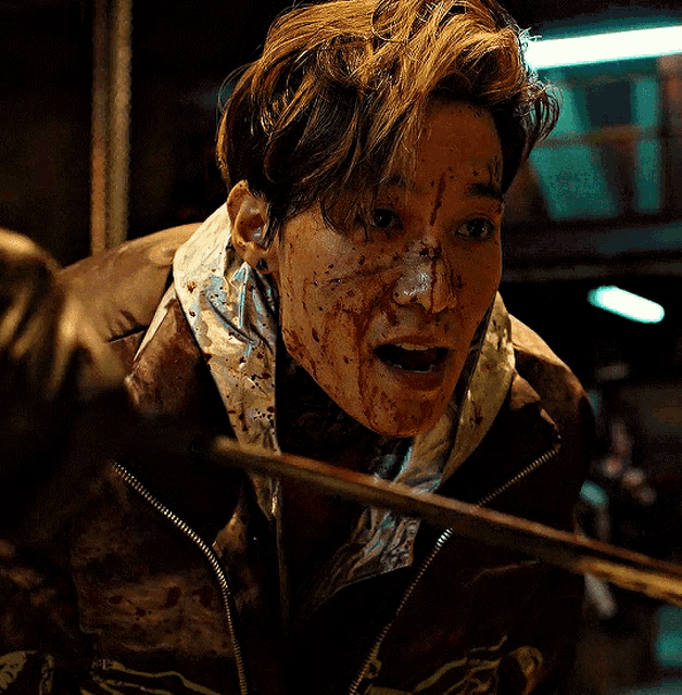 a person with blood on their face is wearing a brown jacket with the letter g on it