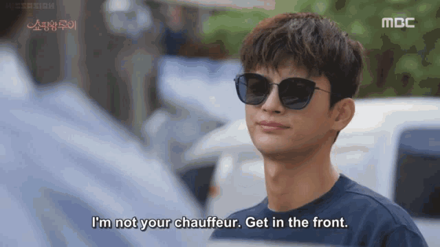 a man wearing sunglasses is saying i 'm not your chauffeur . get in the front .