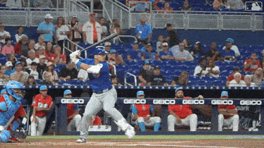 a baseball player is swinging at a pitch in front of a banner that says geico