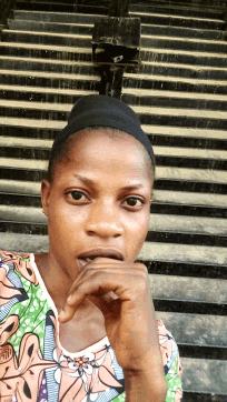 a woman wearing a headband and a floral shirt looks at the camera with her hand on her chin