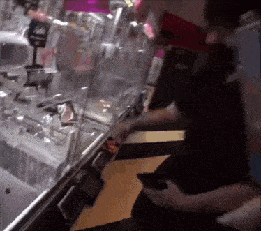 a man is playing a game in an arcade while holding a phone .