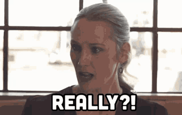 a woman is sitting at a table in front of a window and saying really ?