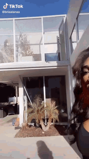 a woman is standing in front of a large house with a tiktok watermark on the bottom right