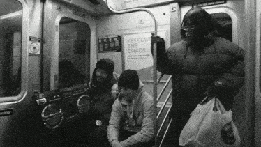 a black and white photo of people on a train with a keep out the chaos sign