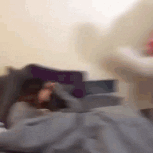 a blurry picture of a person laying on a bed with a purple pillow