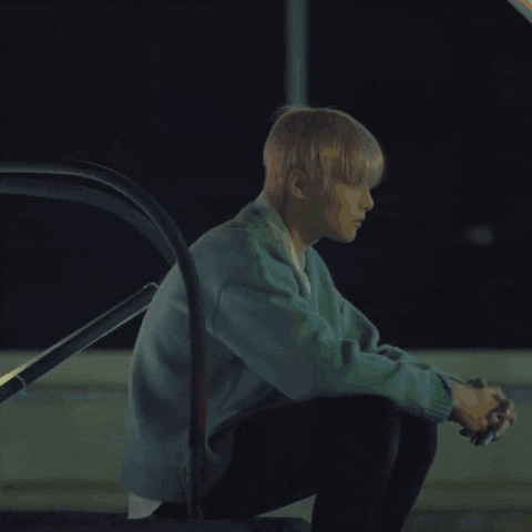 a man in a blue sweater sits on the ground