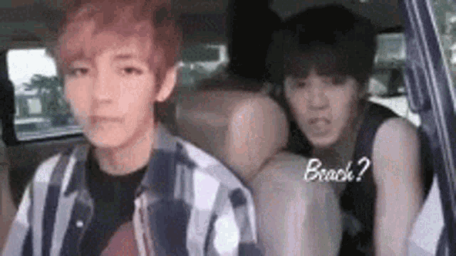 two young men are sitting in the back seat of a car and one of them is talking to the other .