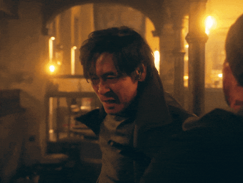 a man in a dark room with candles on the walls