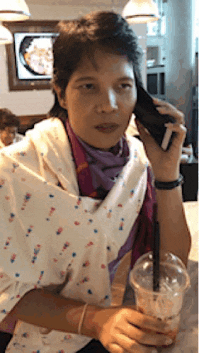 a woman is talking on a cell phone while holding a cup of coffee