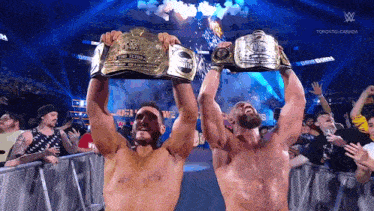two wrestlers holding up their championship belts in front of a crowd in toronto canada