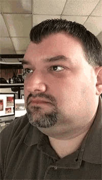 a man with a beard and a gray shirt looks at the camera
