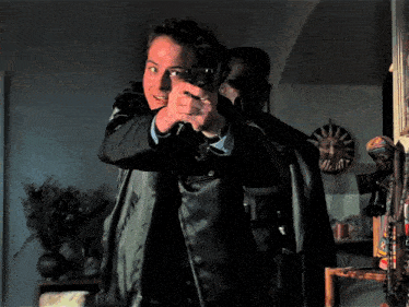 a man pointing a gun at another man in a dark room