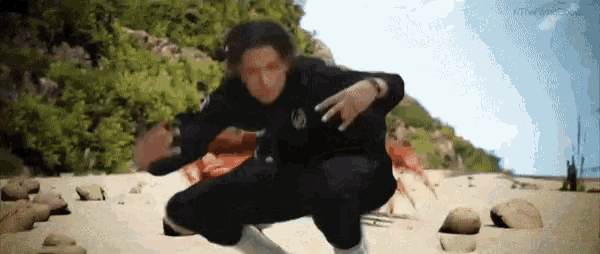 a man in a wetsuit is squatting on a beach