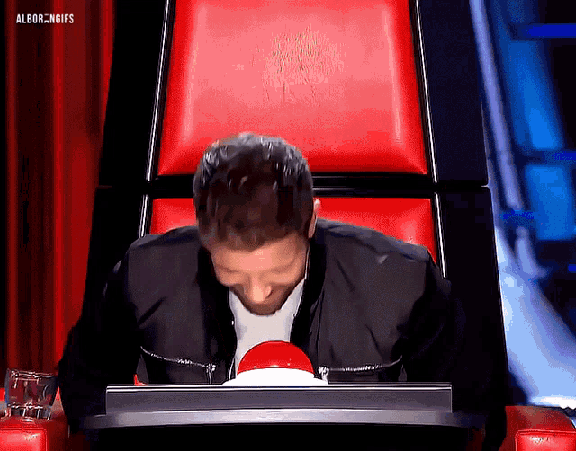 a man sitting in a chair with a red button in front of him that says albor.ngifs on the bottom