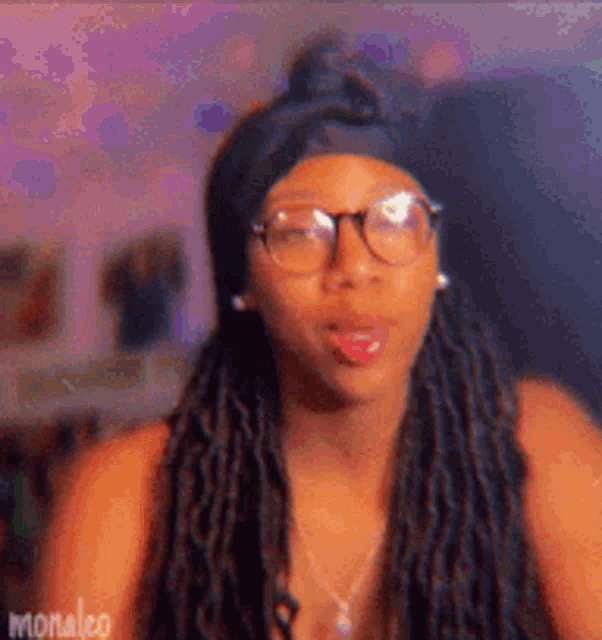 a woman with dreadlocks is wearing glasses and a headband and sticking her tongue out .