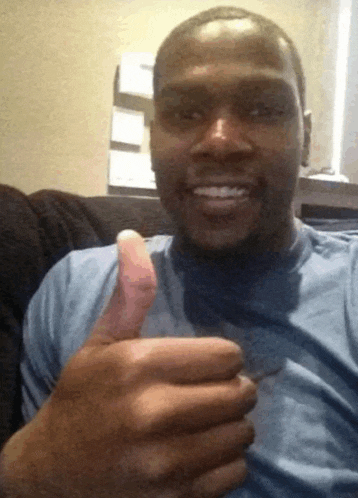 a man in a blue shirt is giving a thumbs up sign