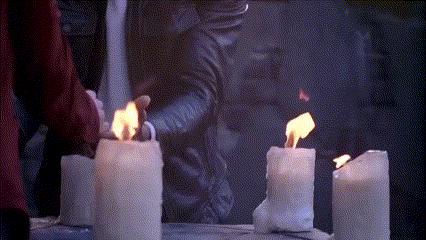 a row of white candles are lit up in the dark