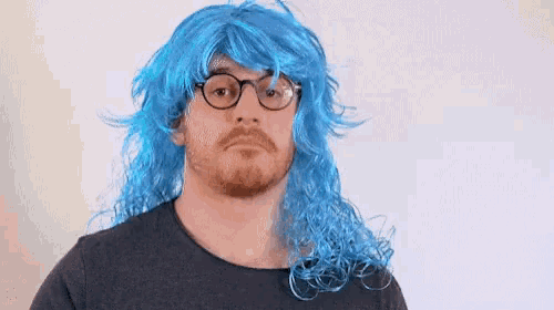 a man wearing a blue wig and glasses is making a face .