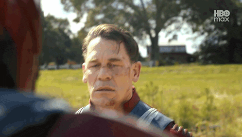 a man in a superhero costume is talking to another man in a field with hbo max written on the bottom