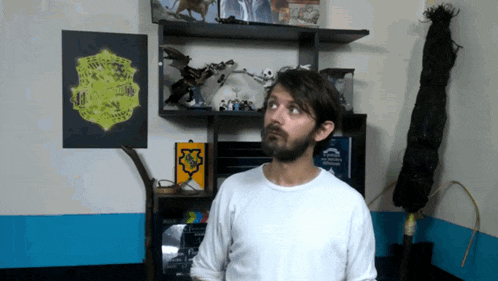 a man in a white shirt stands in front of a shelf with a map of the world on it