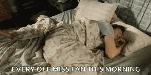 a woman is sleeping in a bed with the words `` every ole miss fan this morning '' written on the bottom .