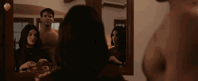 a man and a woman are looking at their reflections in a mirror