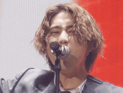 a man with long hair singing into a microphone