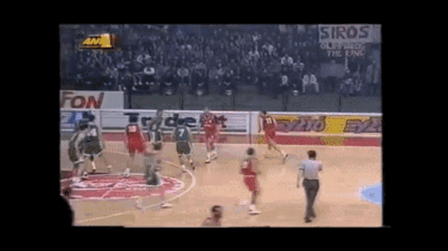a basketball game is being played in front of a crowd with an ad for siros in the background
