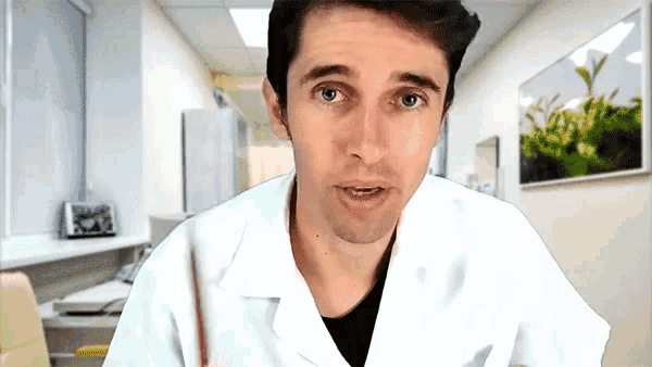 a man in a lab coat is holding a pencil and looking at the camera
