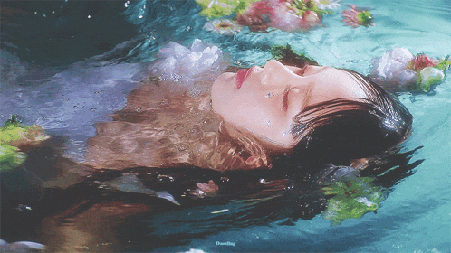 a woman is floating in a body of water with flowers in her hair
