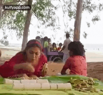 a woman and a child are sitting at a table on the beach .