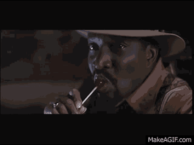 a man in a cowboy hat is eating a lollipop .