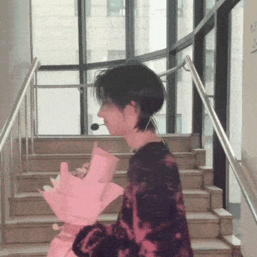 a person standing on a set of stairs holding a pink bouquet of flowers