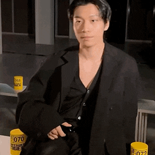 a man in a black suit is sitting next to a yellow cup that says 070 on it .