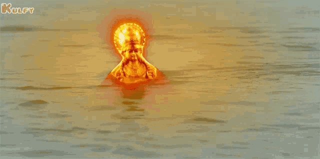 a statue of a man is floating in the water and the letters kulfy are visible on the bottom