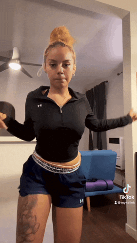 a woman wearing under armour shorts is dancing in a room