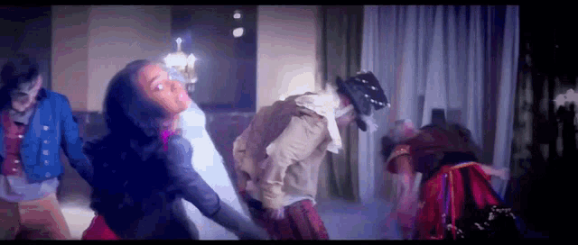 a group of people are dancing in a room with a chandelier in the background .