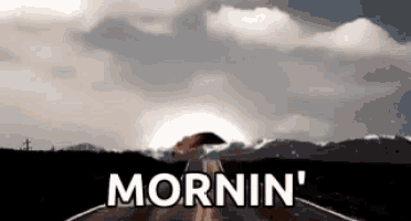a person holding an umbrella on the side of a road with the words mornin ' written on it .
