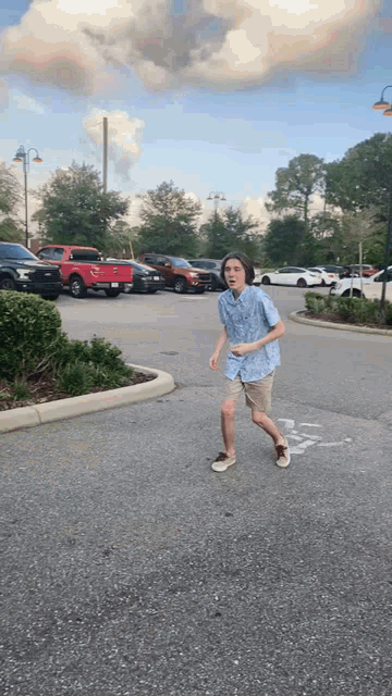 a boy in a blue shirt and khaki shorts is running down the street
