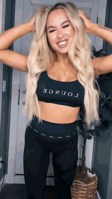 a blonde woman wearing a black crop top that says " lon " on it