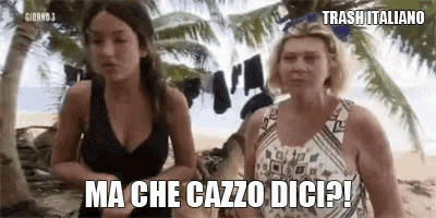 two women are standing on a beach with clothes hanging on a clothes line .