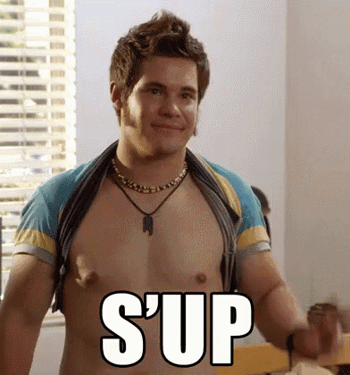 a shirtless man is standing in front of a window with the word sup written on his chest .