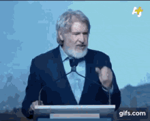 a man in a suit and tie is giving a speech at a podium with gifs.com at the bottom of the screen