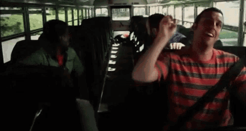 a man in a striped shirt is sitting in the back of a school bus