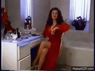 a woman in a red dress is sitting in a chair in front of a vanity ..