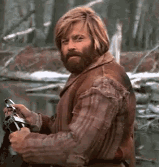 a man with long hair and a beard is holding a sword in his hand .