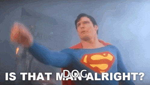 a man in a superman costume is holding his fist up in the air and says `` is that man alright ? ''