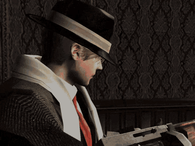 a man in a hat holds a gun in front of a wall