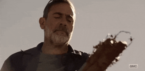 a man with a beard is holding a broken guitar in his hands .