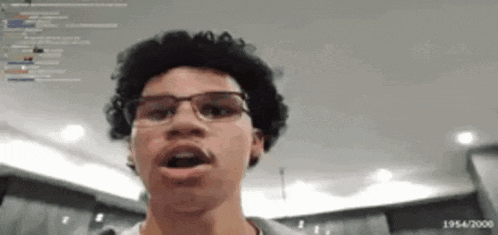 a young man with curly hair and glasses is looking at the camera .